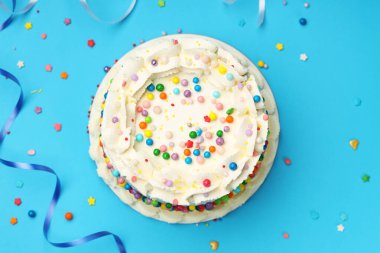 Rengarenk serpiştirilmiş nefis bento keki ve açık mavi masada serebentin şeritler, düz uzanmış.