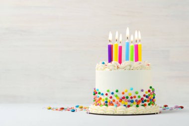 Renkli süslemeli nefis bento keki ve beyaz masada yanan mumlar. Metin için boşluk