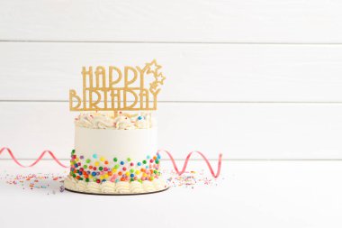 Lezzetli bento keki, üzerine renkli süslemeler, süslemeler ve beyaz masa üzerinde serpentin şeritler. Metin için boşluk