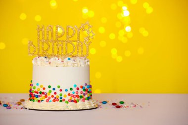 Renkli süslemeli lezzetli bento keki ve masanın üstünde sarı arka plan, yazı için yer var. Bokeh etkisi