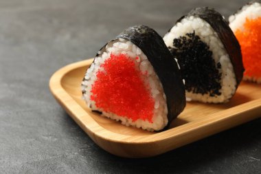 Lezzetli tobiko onigiri (Japon pirinç topları) siyah masada, yakın plan