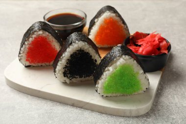 Lezzetli tobiko onigiri (Japon pirinç topları) açık gri masada servis edilir.