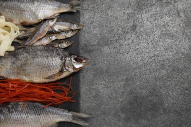 Gri masada birçok farklı kurutulmuş balık aperatifleri, üst manzara. Metin için boşluk