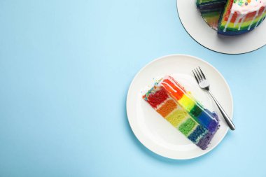 Açık mavi masada nefis bir gökkuşağı pastası, düz uzanmış. Metin için boşluk