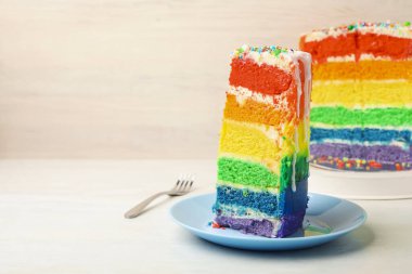 Lezzetli bir parça gökkuşağı pastası beyaz masada, yakın plan. Metin için boşluk