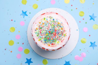 Lezzetli pasta, konfeti ve açık mavi masaya serpiştirilmiş şekerler.