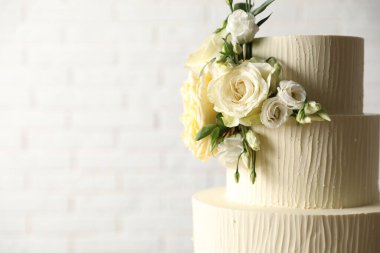 Beyaz arka planda çiçeklerle süslenmiş lezzetli düğün pastası, yakın plan. Metin için boşluk