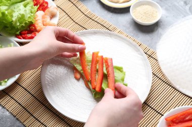 Açık gri masada nefis börek yapan bir kadın.