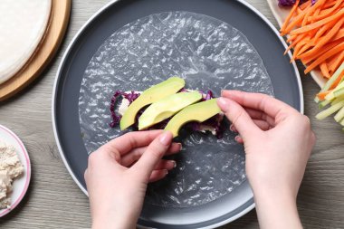 Gri ahşap masada nefis börek yapan bir kadın.