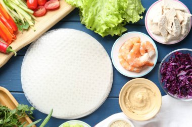 Pirinç kağıt çarşaflar ve mavi ahşap masa üzerindeki farklı malzemeler.