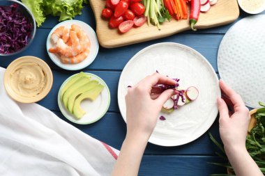 Mavi ahşap masada nefis börek yapan bir kadın.