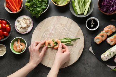 Koyu gri masada nefis börek yapan bir kadın.