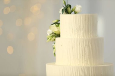 Bulanık arkaplanda çiçek dekoru olan nefis düğün pastası, mesaj için yer. Bokeh etkisi