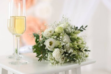 Şampanya bardakları ve düğün buketi kapalı bir masada, yakın plan.