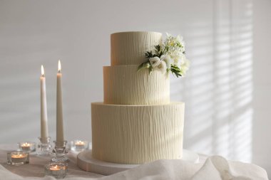 Çiçek desenli nefis düğün pastası ve içeride yanan mumlar.