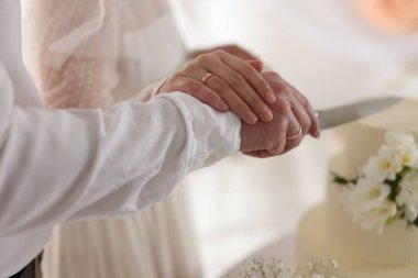 Evli çift içeride bıçakla lezzetli bir düğün pastası kesiyor.