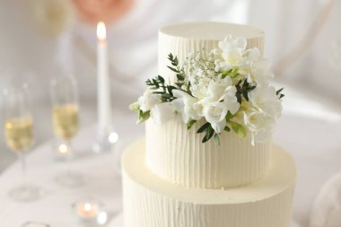 İçerideki masada çiçeklerle süslenmiş nefis düğün pastası, yakın plan.