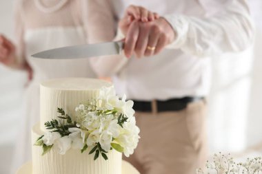 Evli çift içeride bıçakla lezzetli bir düğün pastası kesiyor.