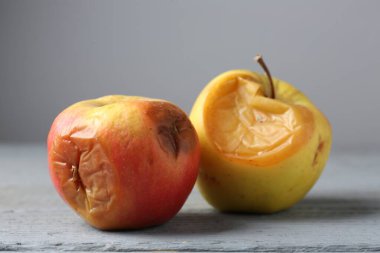 Gri ahşap masada çürük elmalar, yakın plan.