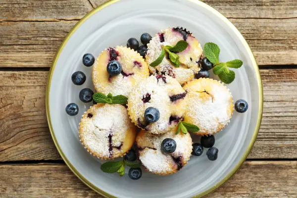 Yaban mersinli lezzetli çörekler, pudra şekeri ve nane şekeri ahşap masa, üst manzara