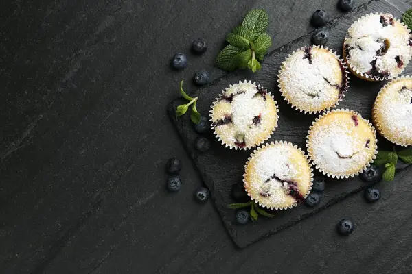 Yaban mersinli lezzetli çörekler, pudra şekeri ve siyah desenli masada nane şekeri, düz yatak. Metin için boşluk