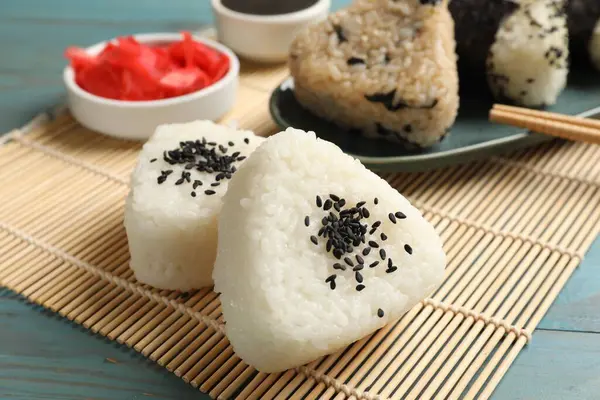 Pirinç topları (onigiri) açık mavi ahşap masada servis edilir. Geleneksel Japon yemeği