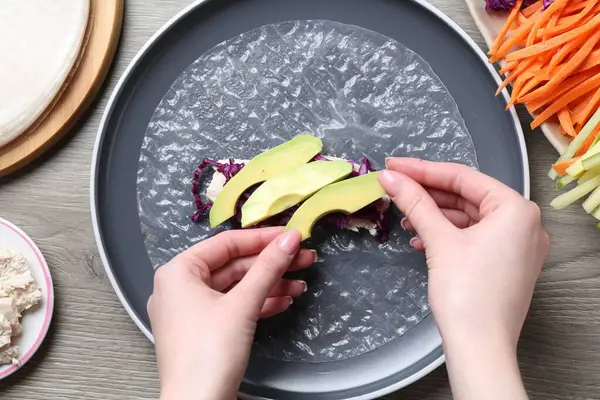 Gri ahşap masada nefis börek yapan bir kadın.