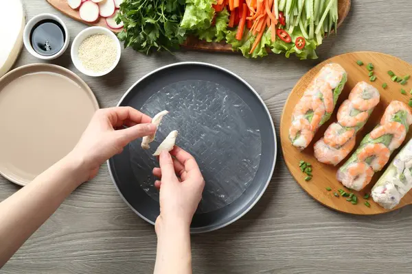 Gri ahşap masada nefis börek yapan bir kadın.