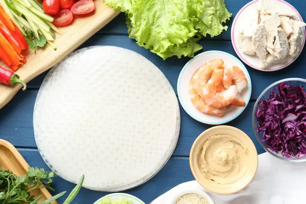 Pirinç kağıt çarşaflar ve mavi ahşap masa üzerindeki farklı malzemeler.