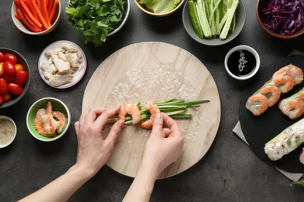 Koyu gri masada nefis börek yapan bir kadın.