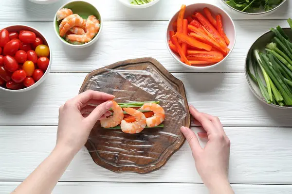 Beyaz ahşap masada nefis börek yapan bir kadın.