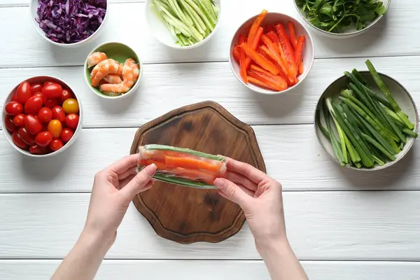 Beyaz ahşap masada nefis börek yapan bir kadın.