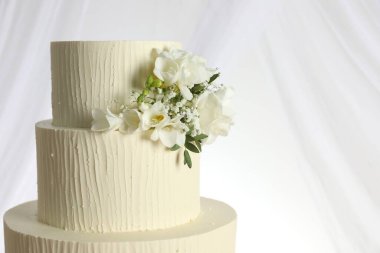 Çiçek desenli nefis düğün pastası ve beyaz arka planda perdeler, yakın plan. Metin için boşluk