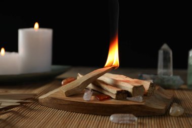 Yanan palo santo sopası, değerli taşlar ve mumlar masada, yakın plan.