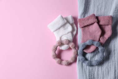Baby blanket, socks and teethers on pink background, flat lay. Space for text