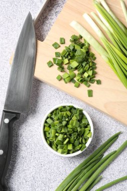 Taze yeşil soğan ve bıçak açık gri masada, düz yatıyordu.