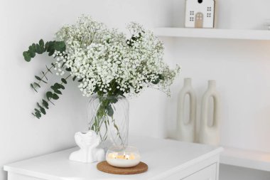 Güzel çigila çiçekleri ve okaliptüs dalları vazoda iç çekmecelerin üzerindeki dekoratif elementlerin yanında.