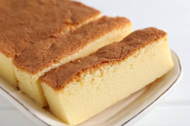 Tasty Japanese Castella sponge cake on white wooden table, closeup