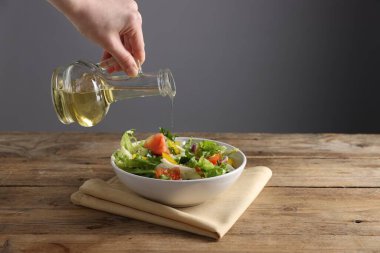 Ahşap masadaki salataya balzamik sirke döken kadın, yakın plan. Metin için boşluk