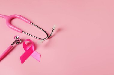 Göğüs kanseri farkındalığı. Renkli arka planda pembe kurdele ve steteskop. Metin için boşluk