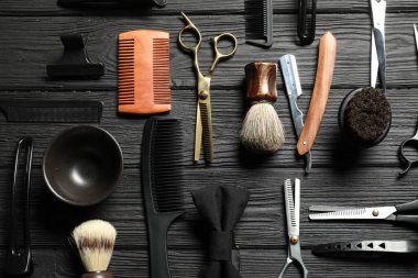 Birçok farklı berber aletleri siyah ahşap masa üzerinde, düz yatıyordu.