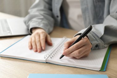 İçerideki ahşap masada notlar alan bir kadın, yakın plan. Kendi kendine çalışma.