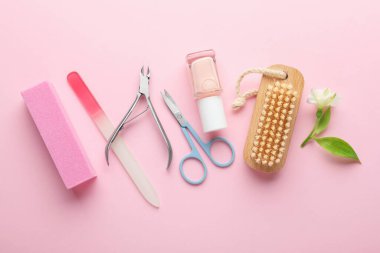 Pembe arka planda farklı manikür aletleri ve çiçek seti.