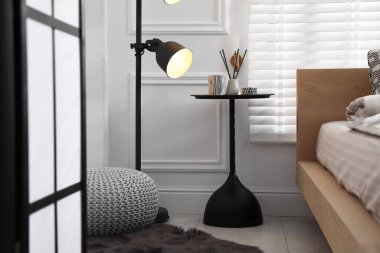 Dekorlu yan masa ve yatağın yanındaki lamba. İç tasarım