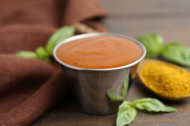 Lezzetli köri sosu metal tabakta, toz ve fesleğen ahşap masada, yakın plan.