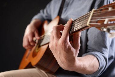 Siyah arka planda gitar çalan adam, ele odaklan.