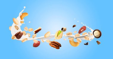 Yulaf gevreği, fındık ve açık mavi arka planda havaya süt sıçratma. Pankart tasarımı