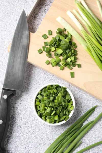 Taze yeşil soğan ve bıçak açık gri masada, düz yatıyordu.