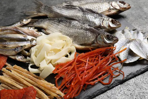 Gri masada birçok farklı kurutulmuş balık atıştırmalıkları, yakın plan.