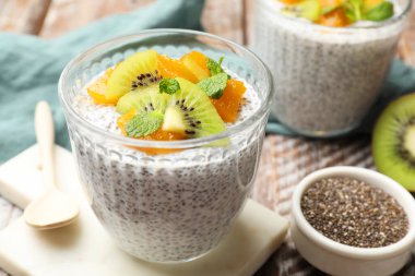 Delicious chia pudding with kiwi, peach and mint in glasses served on table, closeup
